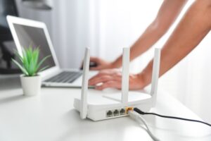 Osoba propojující moderní wi-fi router na světlém stole v obýváku